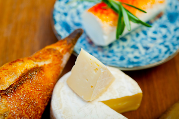 Image showing French cheese and fresh  baguette on a wood cutter