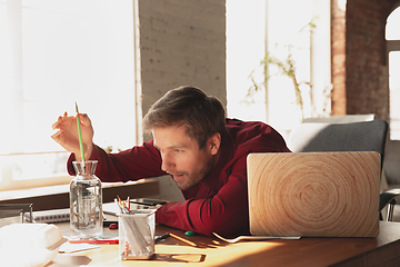 Image showing Caucasian entrepreneur, businessman, manager trying to work, looks funny, lazy and spending time