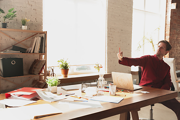 Image showing Caucasian entrepreneur, businessman, manager trying to work, looks funny, lazy and spending time