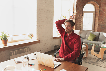 Image showing Caucasian entrepreneur, businessman, manager trying to work, looks funny, lazy and spending time