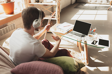 Image showing Young man studying at home during online courses for musician, drummer, producer