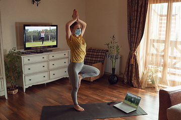 Image showing Sporty young woman taking yoga lessons online and practice at home while being quarantine