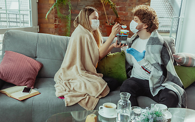 Image showing Woman and man, couple in protective masks and gloves isolated at home with coronavirus symptoms