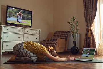 Image showing Sporty young woman taking yoga lessons online and practice at home while being quarantine