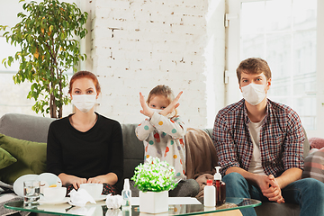 Image showing Caucasian family in protective masks and gloves isolated at home with coronavirus symptoms, stop epidemic