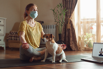 Image showing Sporty young woman taking yoga lessons online and practice at home while being quarantine