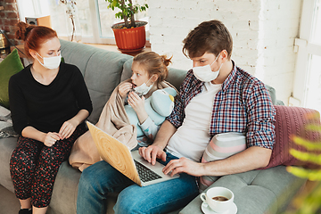 Image showing Caucasian family in protective masks and gloves isolated at home with coronavirus symptoms, treatment