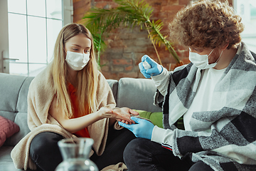 Image showing Woman and man, couple in protective masks and gloves isolated at home with coronavirus symptoms