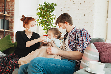 Image showing Caucasian family in protective masks and gloves isolated at home with coronavirus symptoms, treatment