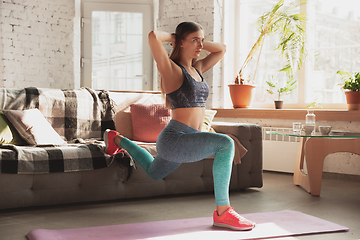 Image showing Young woman teaching at home online courses of fitness, aerobic, sporty lifestyle while being quarantine