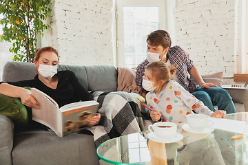 Image showing Caucasian family in protective masks and gloves isolated at home with coronavirus symptoms, treatment