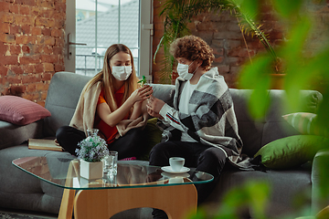 Image showing Woman and man, couple in protective masks and gloves isolated at home with coronavirus symptoms