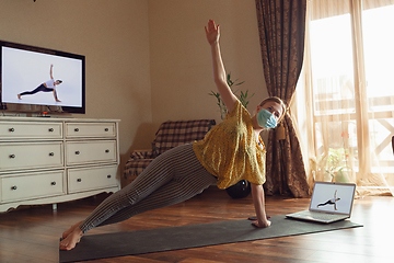 Image showing Sporty young woman taking yoga lessons online and practice at home while being quarantine