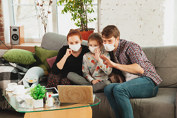 Image showing Caucasian family in protective masks and gloves isolated at home with coronavirus symptoms, treatment