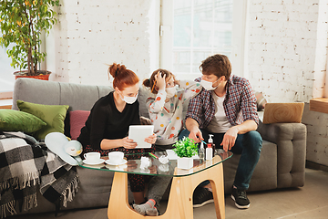 Image showing Caucasian family in protective masks and gloves isolated at home with coronavirus symptoms, treatment