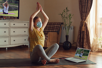 Image showing Sporty young woman taking yoga lessons online and practice at home while being quarantine