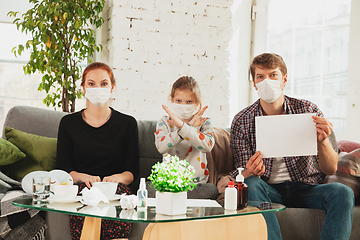 Image showing Caucasian family in protective masks and gloves isolated at home with coronavirus symptoms, stop epidemic