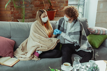 Image showing Woman and man, couple in protective masks and gloves isolated at home with coronavirus symptoms