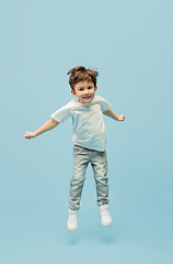 Image showing Happy caucasian little boy isolated on blue studio background. Looks happy, cheerful, sincere. Copyspace. Childhood, education, emotions concept