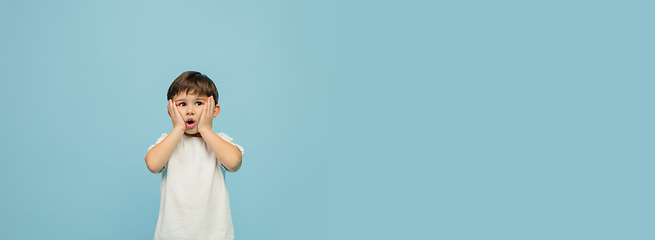 Image showing Happy caucasian little boy isolated on blue studio background. Looks happy, cheerful, sincere. Copyspace. Childhood, education, emotions concept