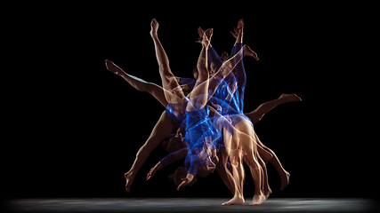 Image showing Young flexible girl on black studio background in strobe and neon light. Young female model practicing artistic gymnastics.