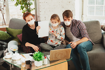 Image showing Caucasian family in protective masks and gloves isolated at home with coronavirus symptoms, treatment