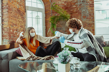 Image showing Woman and man, couple in protective masks and gloves isolated at home with coronavirus symptoms