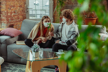 Image showing Woman and man, couple in protective masks and gloves isolated at home with coronavirus symptoms