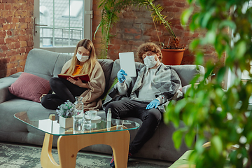 Image showing Woman and man, couple in protective masks and gloves isolated at home with coronavirus symptoms