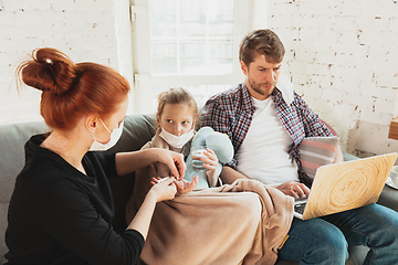 Image showing Caucasian family in protective masks and gloves isolated at home with coronavirus symptoms, treatment