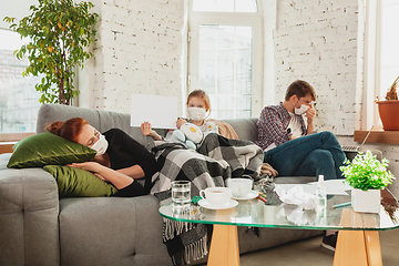 Image showing Caucasian family in protective masks and gloves isolated at home with coronavirus symptoms, treatment