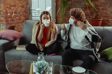 Image showing Woman and man, couple in protective masks and gloves isolated at home with coronavirus symptoms