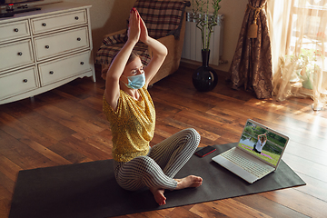 Image showing Sporty young woman taking yoga lessons online and practice at home while being quarantine