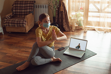 Image showing Sporty young woman taking yoga lessons online and practice at home while being quarantine