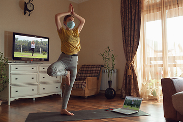 Image showing Sporty young woman taking yoga lessons online and practice at home while being quarantine