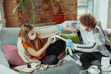 Image showing Woman and man, couple in protective masks and gloves isolated at home with coronavirus symptoms