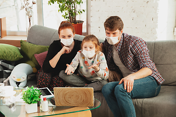 Image showing Caucasian family in protective masks and gloves isolated at home with coronavirus symptoms, treatment