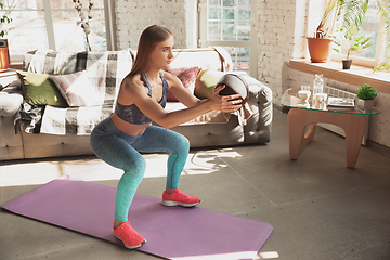 Image showing Young woman teaching at home online courses of fitness, aerobic, sporty lifestyle while being quarantine