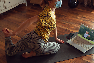 Image showing Sporty young woman taking yoga lessons online and practice at home while being quarantine