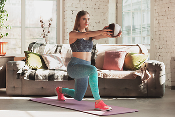 Image showing Young woman teaching at home online courses of fitness, aerobic, sporty lifestyle while being quarantine