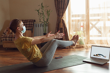 Image showing Sporty young woman taking yoga lessons online and practice at home while being quarantine