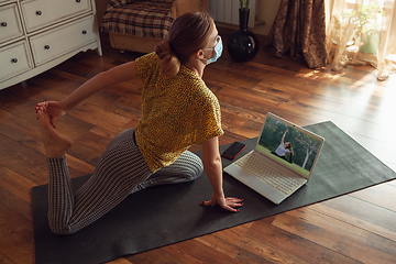 Image showing Sporty young woman taking yoga lessons online and practice at home while being quarantine