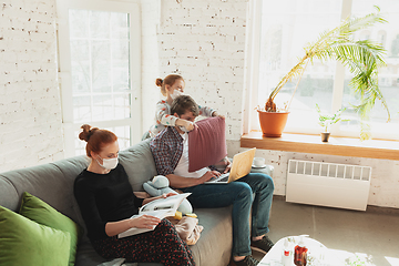 Image showing Caucasian family in protective masks and gloves isolated at home with coronavirus symptoms, treatment