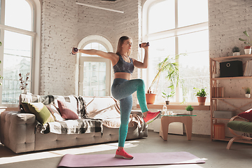 Image showing Young woman teaching at home online courses of fitness, aerobic, sporty lifestyle while being quarantine