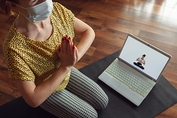 Image showing Sporty young woman taking yoga lessons online and practice at home while being quarantine