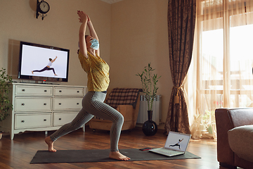 Image showing Sporty young woman taking yoga lessons online and practice at home while being quarantine