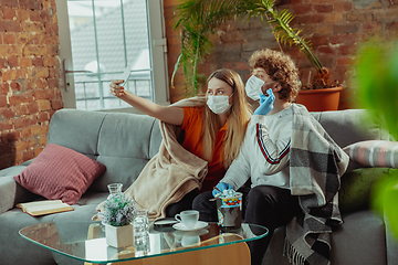 Image showing Woman and man, couple in protective masks and gloves isolated at home with coronavirus symptoms