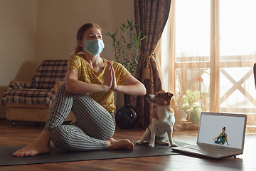 Image showing Sporty young woman taking yoga lessons online and practice at home while being quarantine