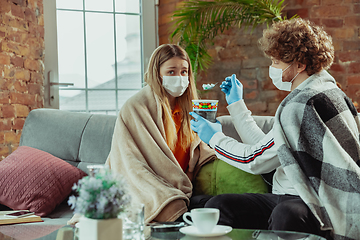 Image showing Woman and man, couple in protective masks and gloves isolated at home with coronavirus symptoms