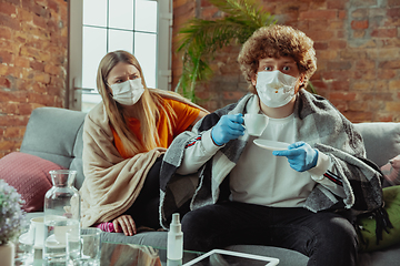 Image showing Woman and man, couple in protective masks and gloves isolated at home with coronavirus symptoms